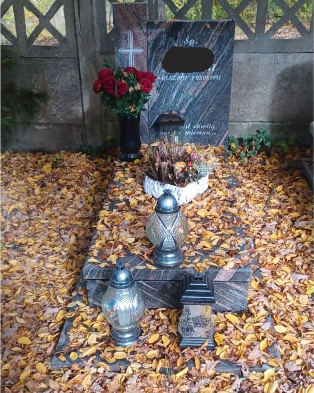 Nagrobek przykryty liśćmi przed uporządkowaniem
